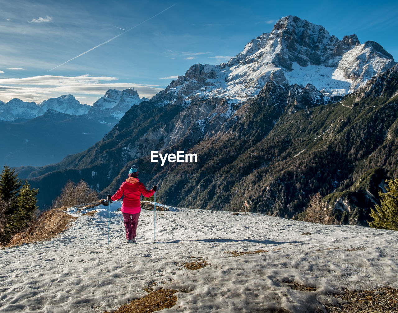 Rear view of woman hiking on snowcapped mountain against sky