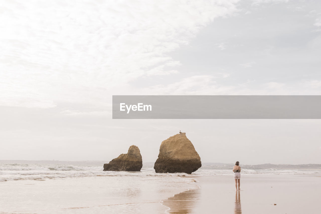 Woman walking at beach against sky