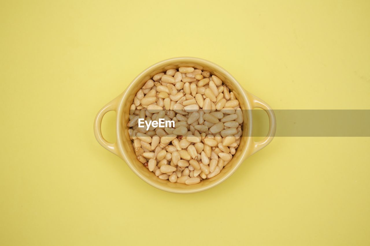 Pignoli in a yellow bowl on yellow background