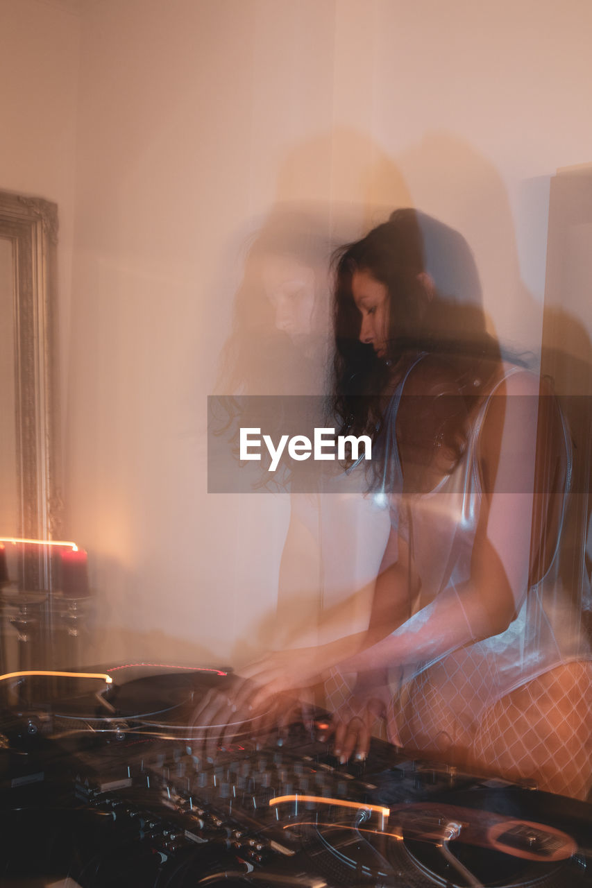 Blurred motion of young woman playing music at home