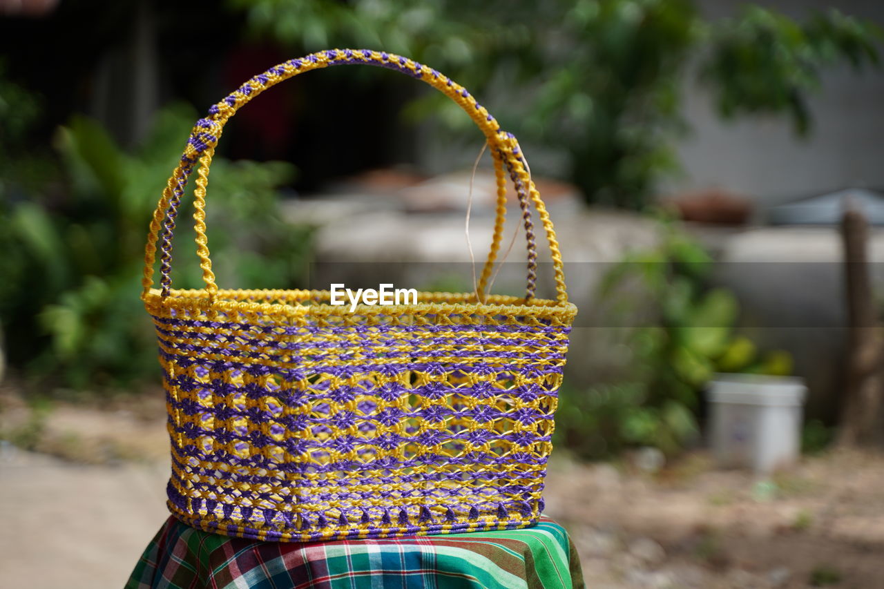 CLOSE-UP OF MULTI COLORED WICKER BASKET WITH YELLOW BACKGROUND