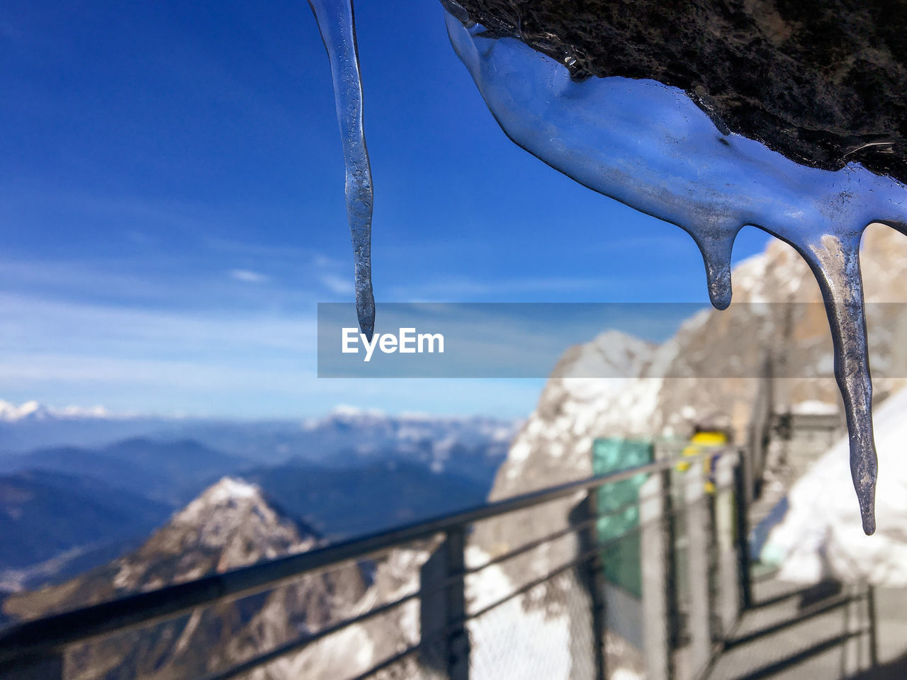 CLOSE-UP OF ICICLES AGAINST MOUNTAINS
