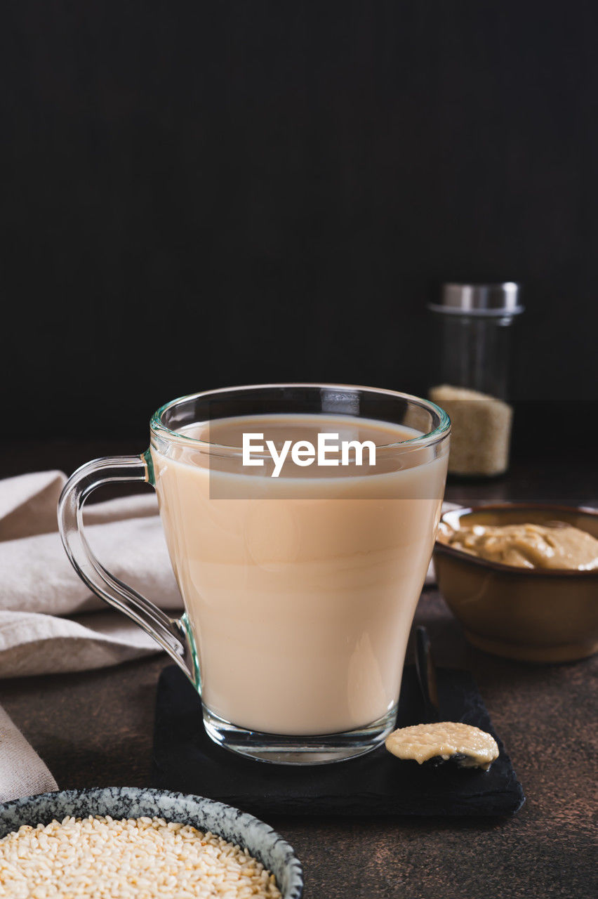food and drink, drink, refreshment, food, studio shot, coffee, glass, dairy, drinking glass, indoors, cup, black background, milk, crockery, household equipment, freshness, hot drink, no people, mug, still life, dark, copy space, healthy eating, latte, wood, coffee cup, sweet food, table, kitchen utensil