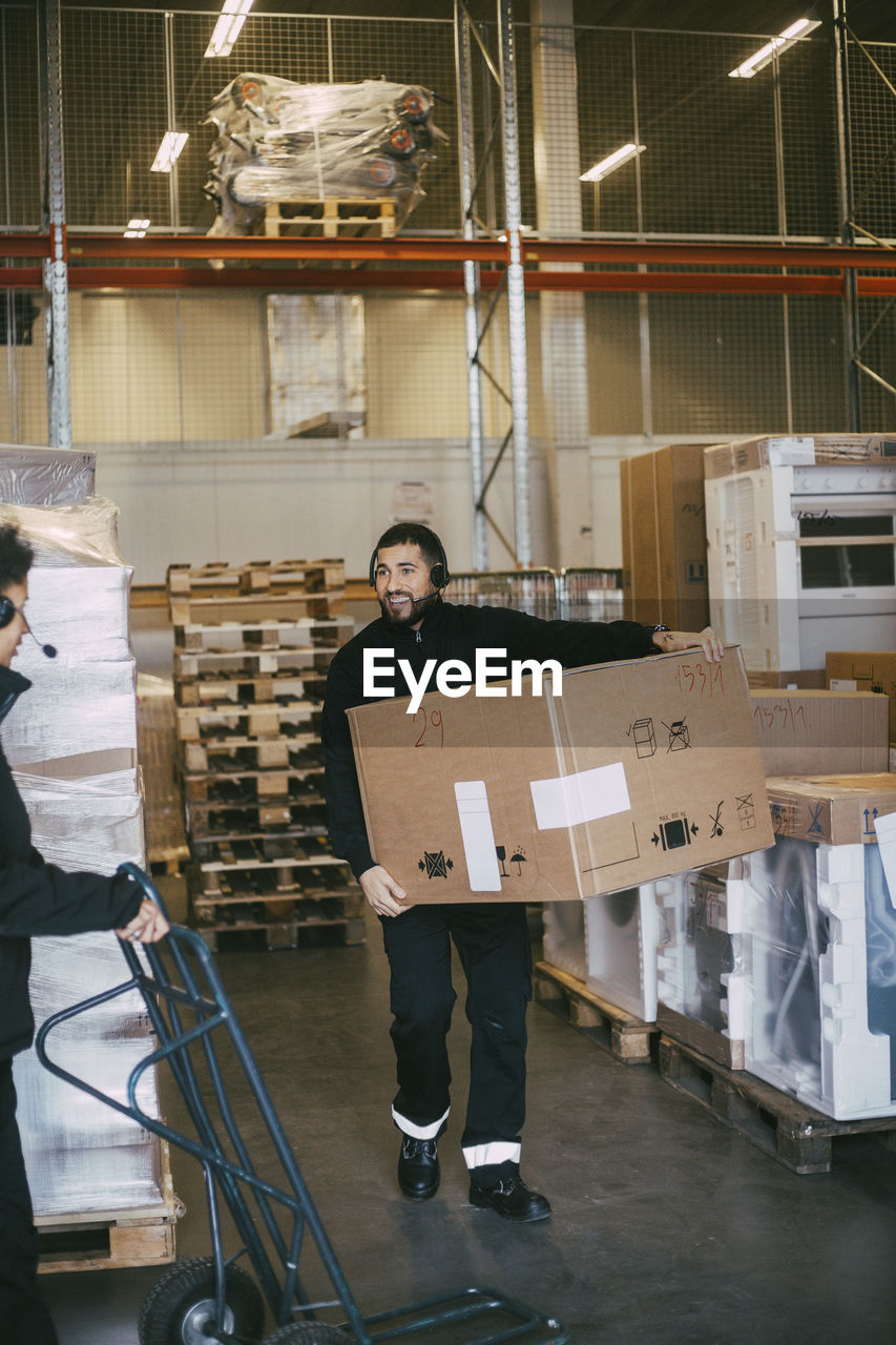 Male entrepreneur carrying box container at distribution warehouse