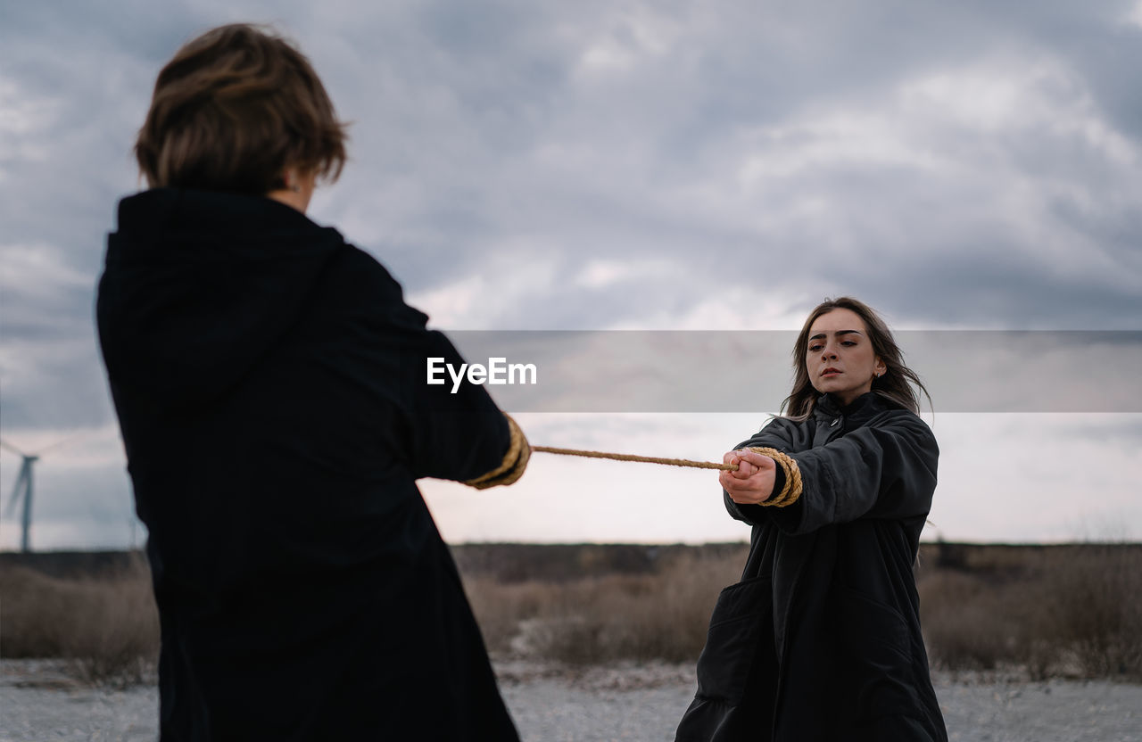Two young women pulling rope on the beach