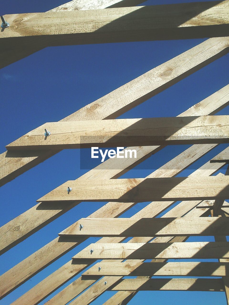 Low angle view of wooden roof against clear blue sky