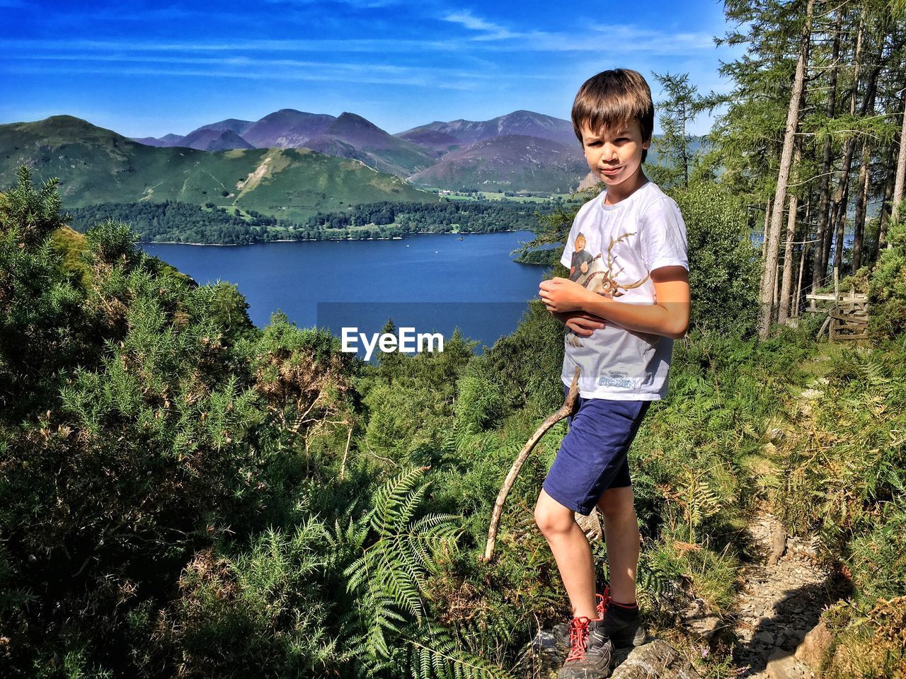 Full length portrait of boy standing by derwent water and mountains against sky