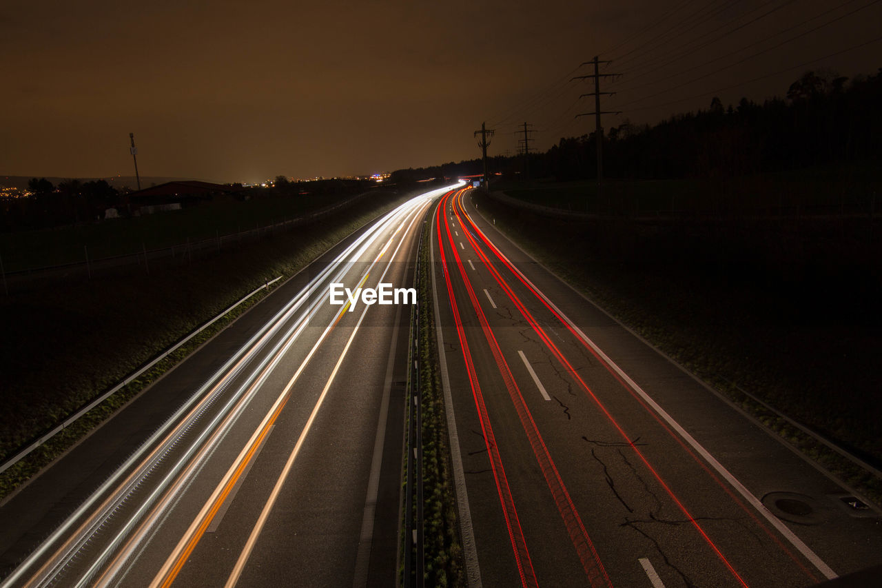 Light trails on road against sky at night