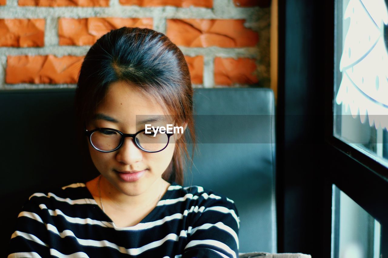 Close-up of young woman sitting by window at cafe