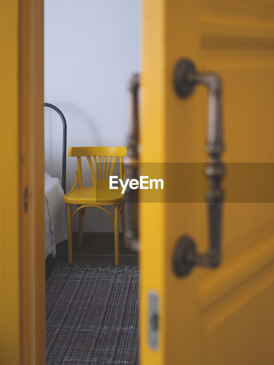 Edge of the bed and a next standing chair from half-open door