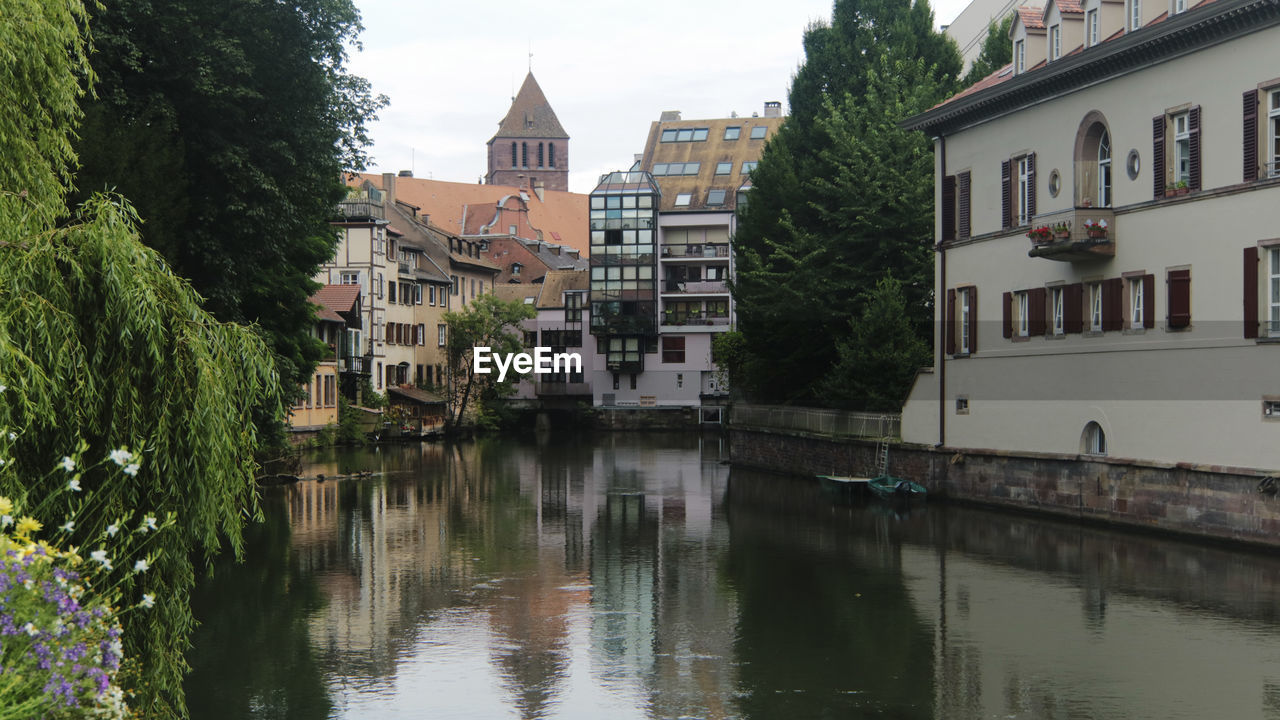 River by buildings in city against sky