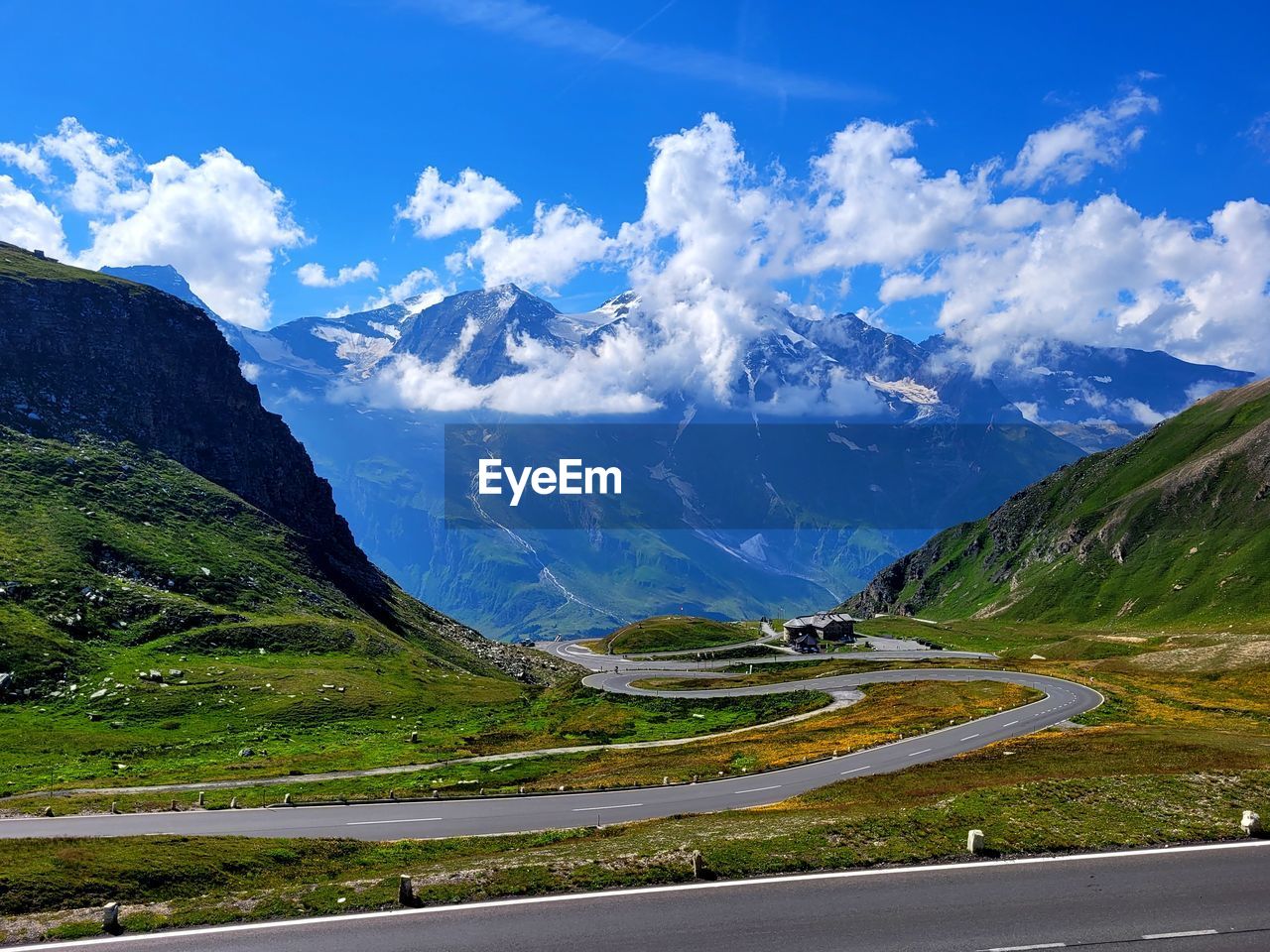 mountain, scenics - nature, mountain range, environment, landscape, road, beauty in nature, mountain pass, sky, nature, transportation, snow, cloud, land, valley, cold temperature, highland, travel, travel destinations, blue, no people, snowcapped mountain, tranquil scene, tranquility, winter, mountain peak, non-urban scene, highway, grass, idyllic, street, plant, water, glacial landform, tourism, plateau, green, outdoors, curve, field, rural scene, day, environmental conservation, summer, winding road, glacier, vacation, activity, social issues, ice, trip, holiday, the way forward, lake, vibrant color, mountain road, sunlight