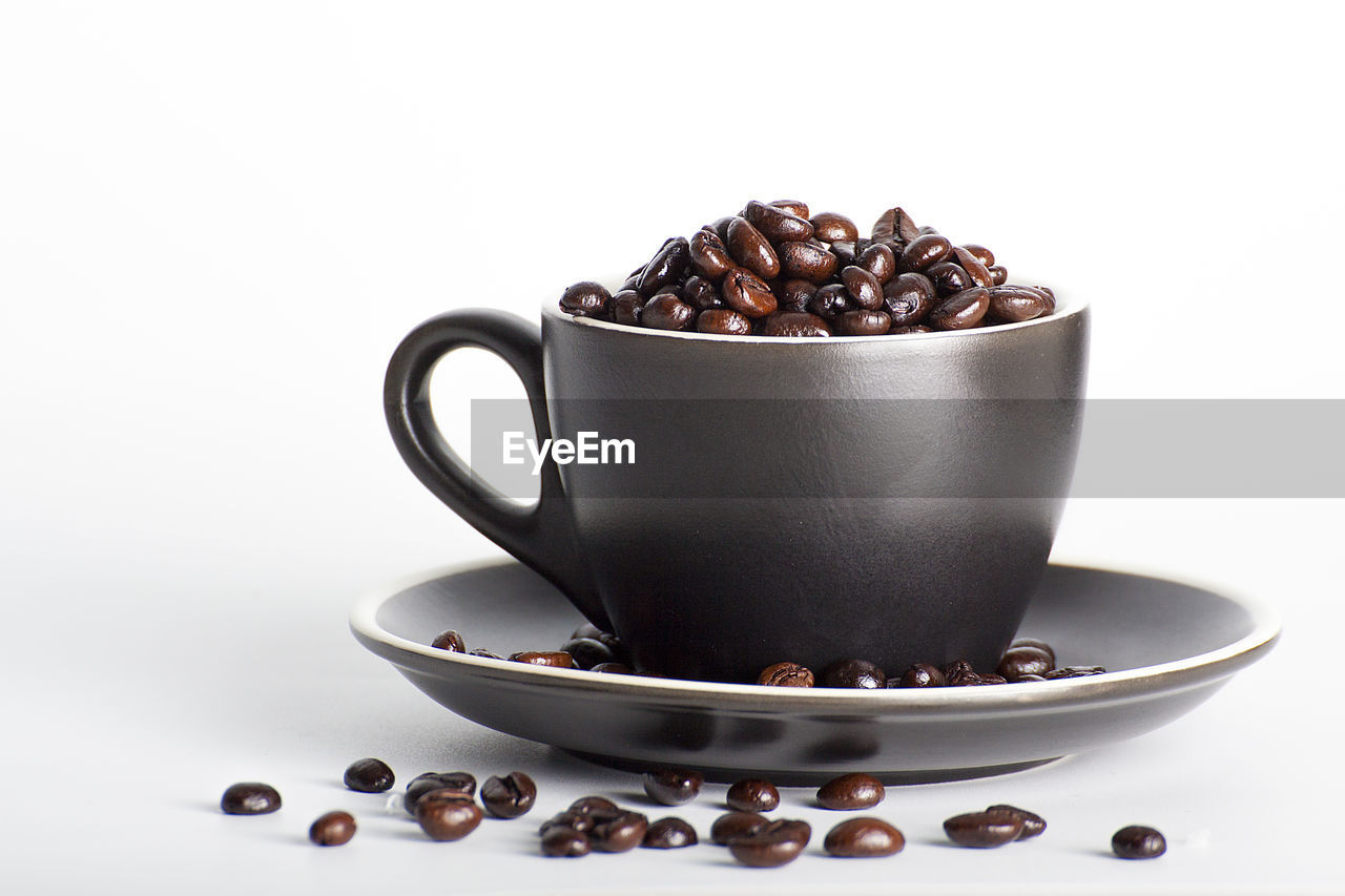 CLOSE-UP OF COFFEE CUP WITH SPOON AND WHITE BACKGROUND