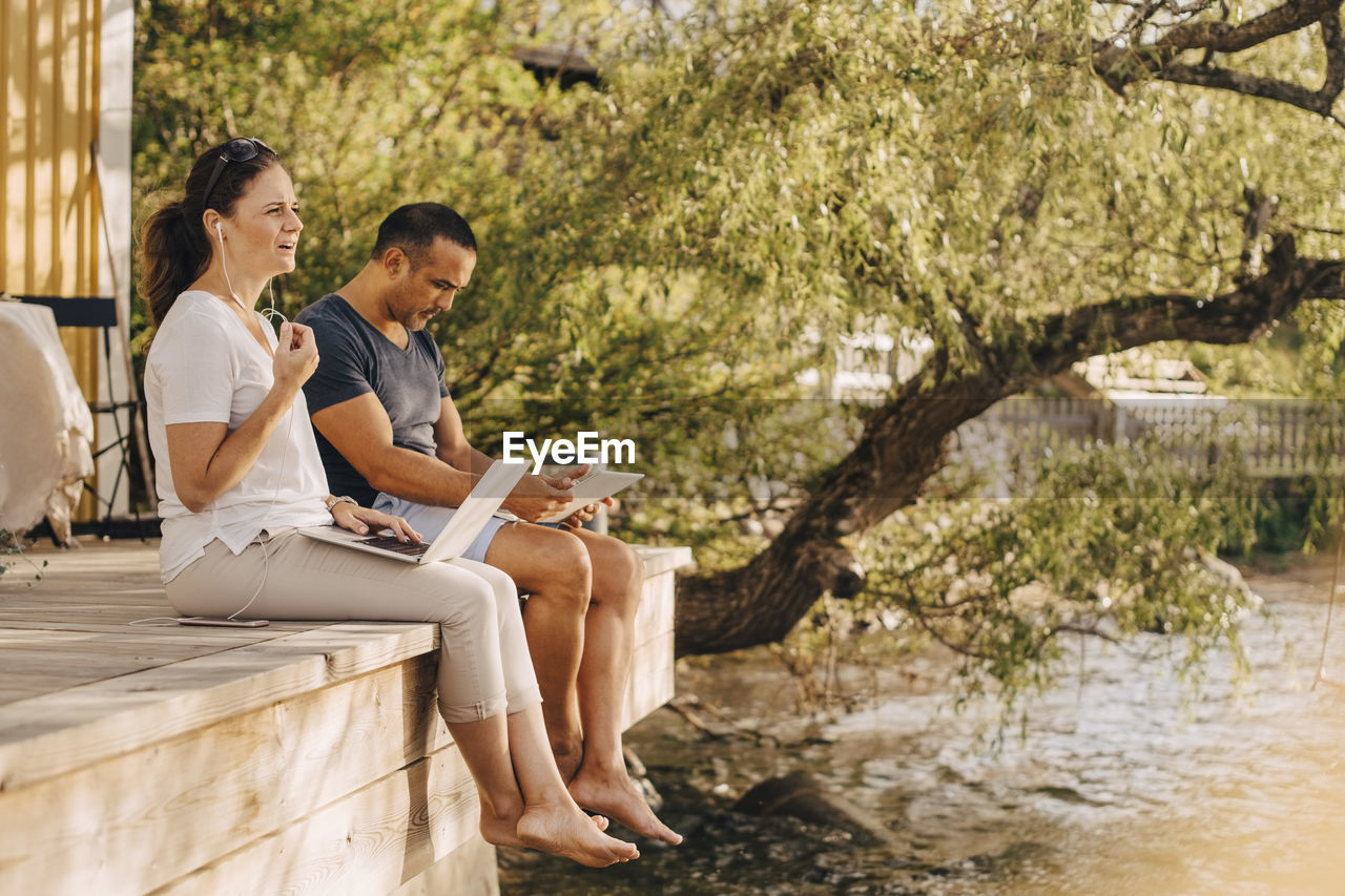 Mature couple using laptops while sitting at patio in holiday villa