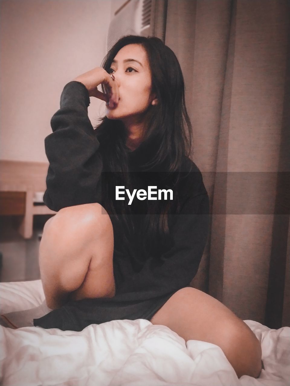 YOUNG WOMAN SITTING IN BED AT HOME