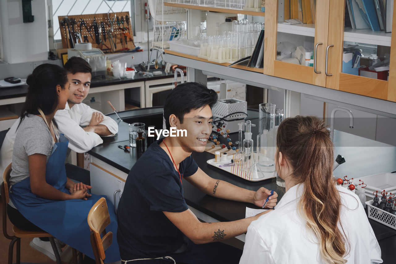High angle view of multi-ethnic young university students sitting on chairs in chemistry laboratory