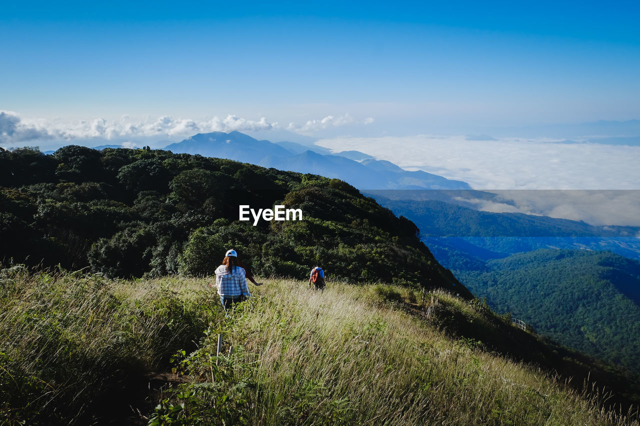 High angle view of hikers hiking on mountain against blue sky