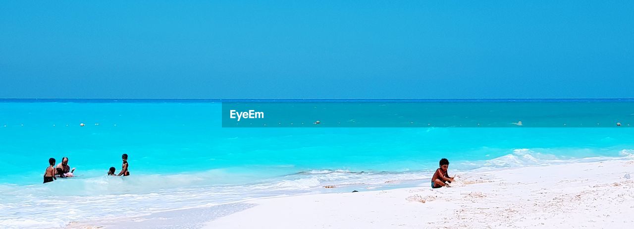 PEOPLE ON SHORE AGAINST CLEAR SKY