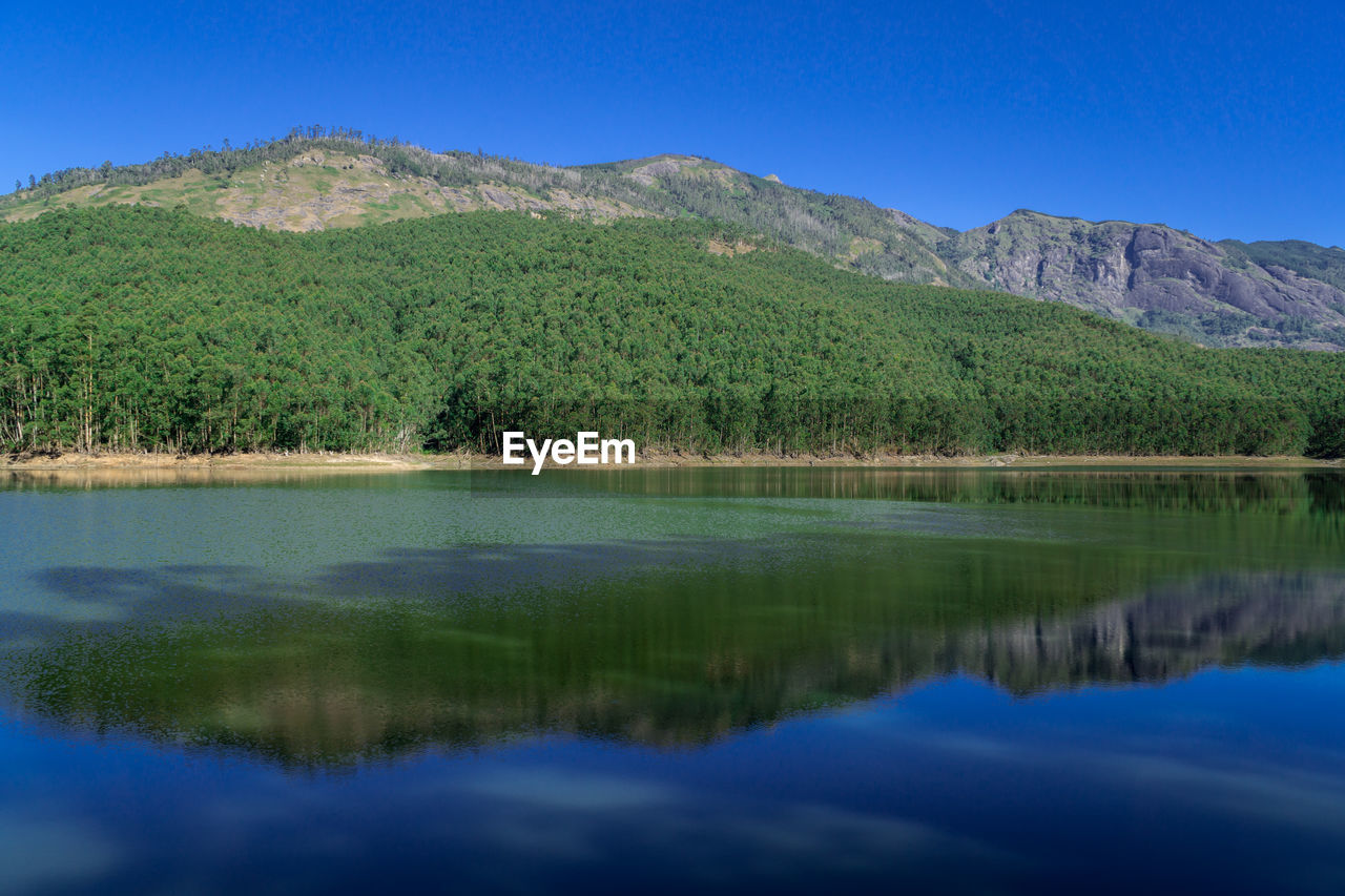 Scenic view of lake and mountains against blue sky