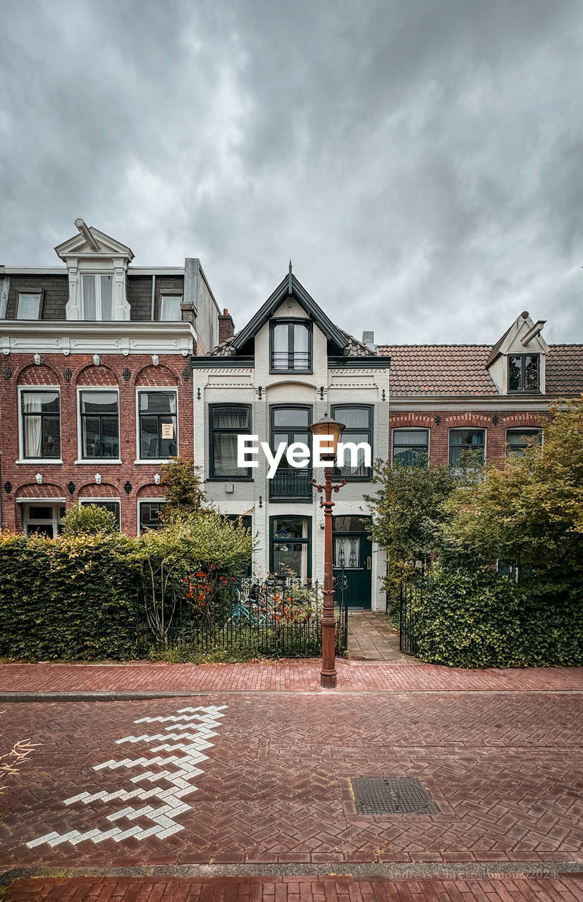 architecture, building exterior, residential area, built structure, building, suburb, neighbourhood, house, home, estate, cloud, residential district, sky, urban area, city, nature, facade, home ownership, street, mansion, town, outdoors, plant, day, front or back yard, footpath, brick, adult, tree
