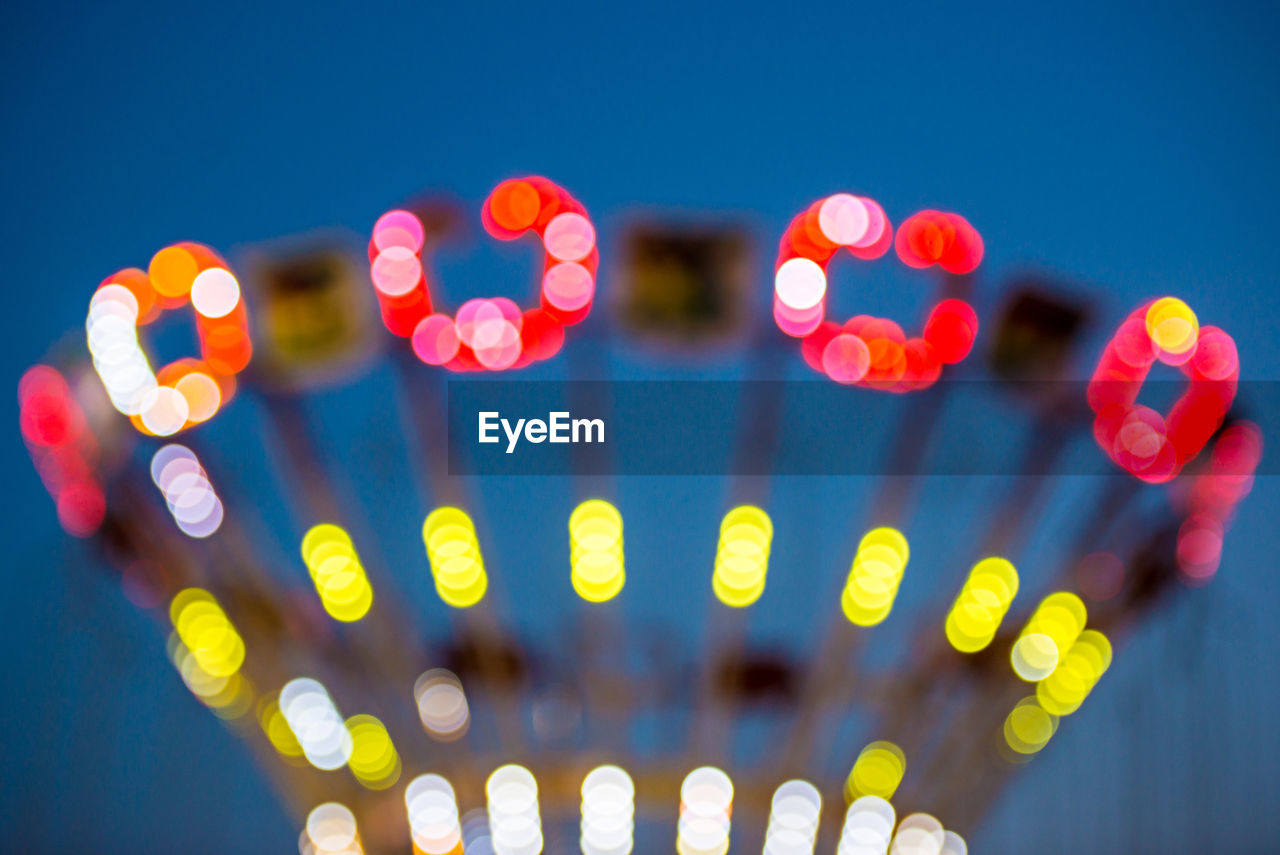 Defocused image of illuminated amusement park ride at night