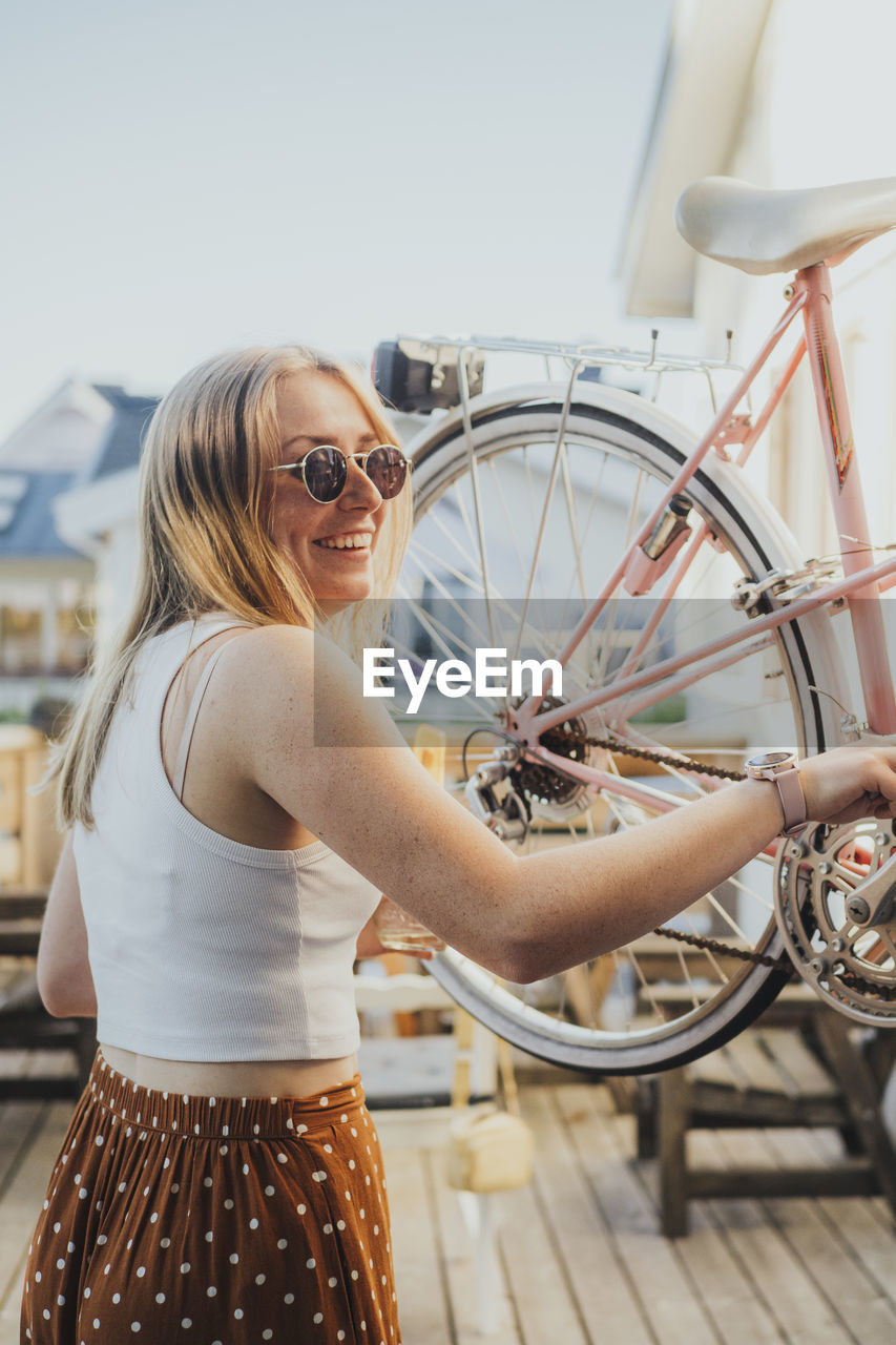 Smiling woman holding bicycle