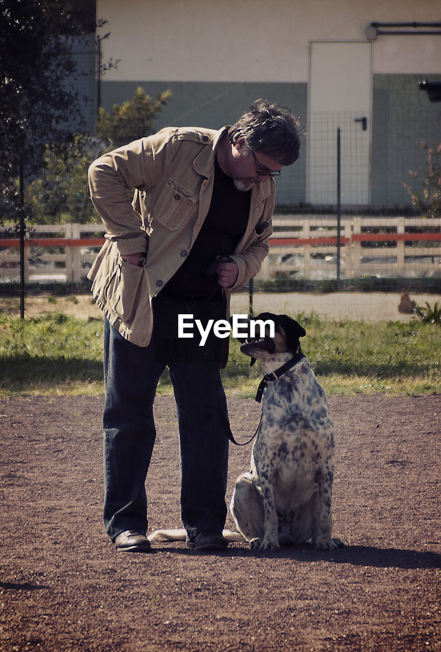 Mature man with dog standing on field