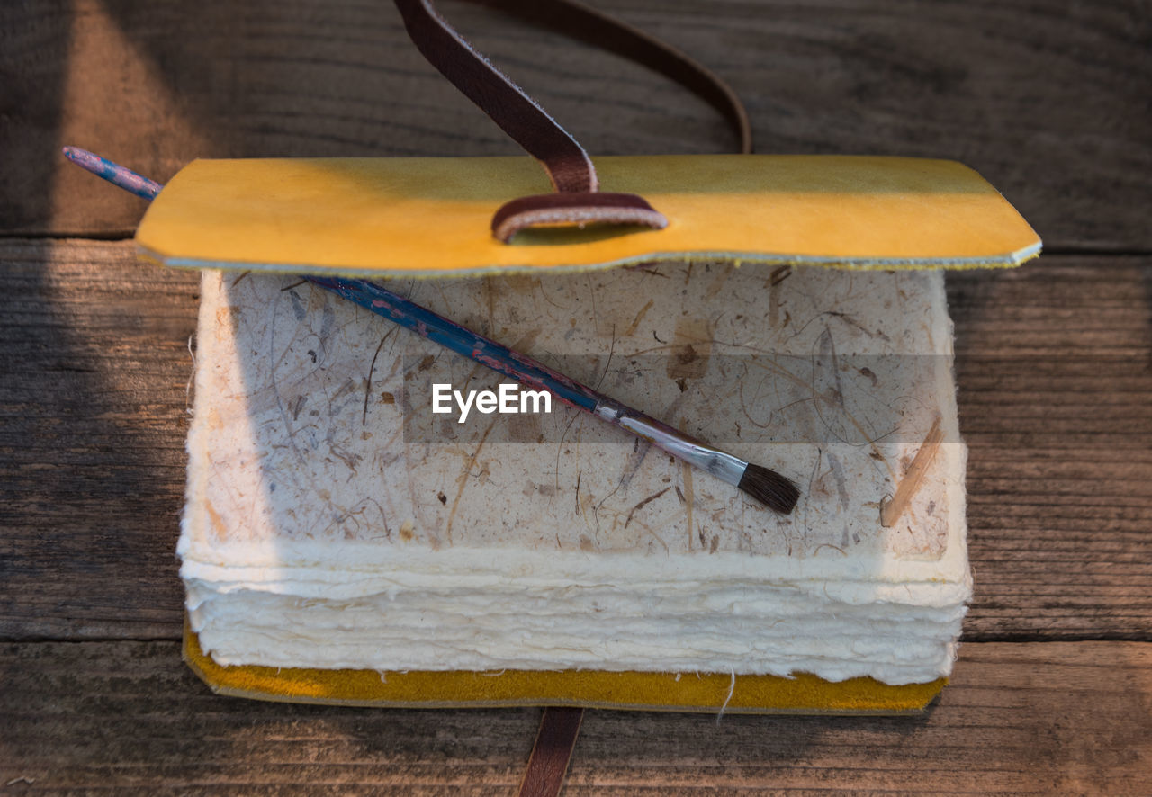 High angle view of paintbrush on book at wooden table