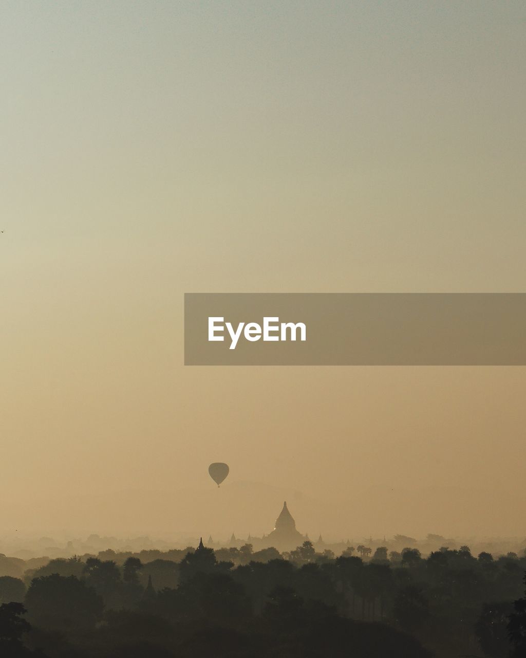 Mid distance view of hot air balloon and temple during sunset