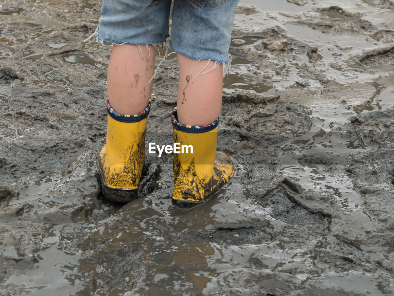 Low section of child standing on mud