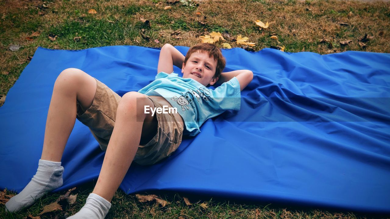 High angle view of boy lying on blanket at filed