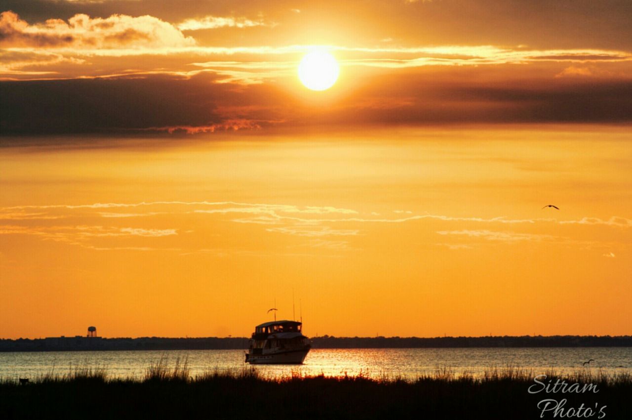 Boat on sea against orange sunset
