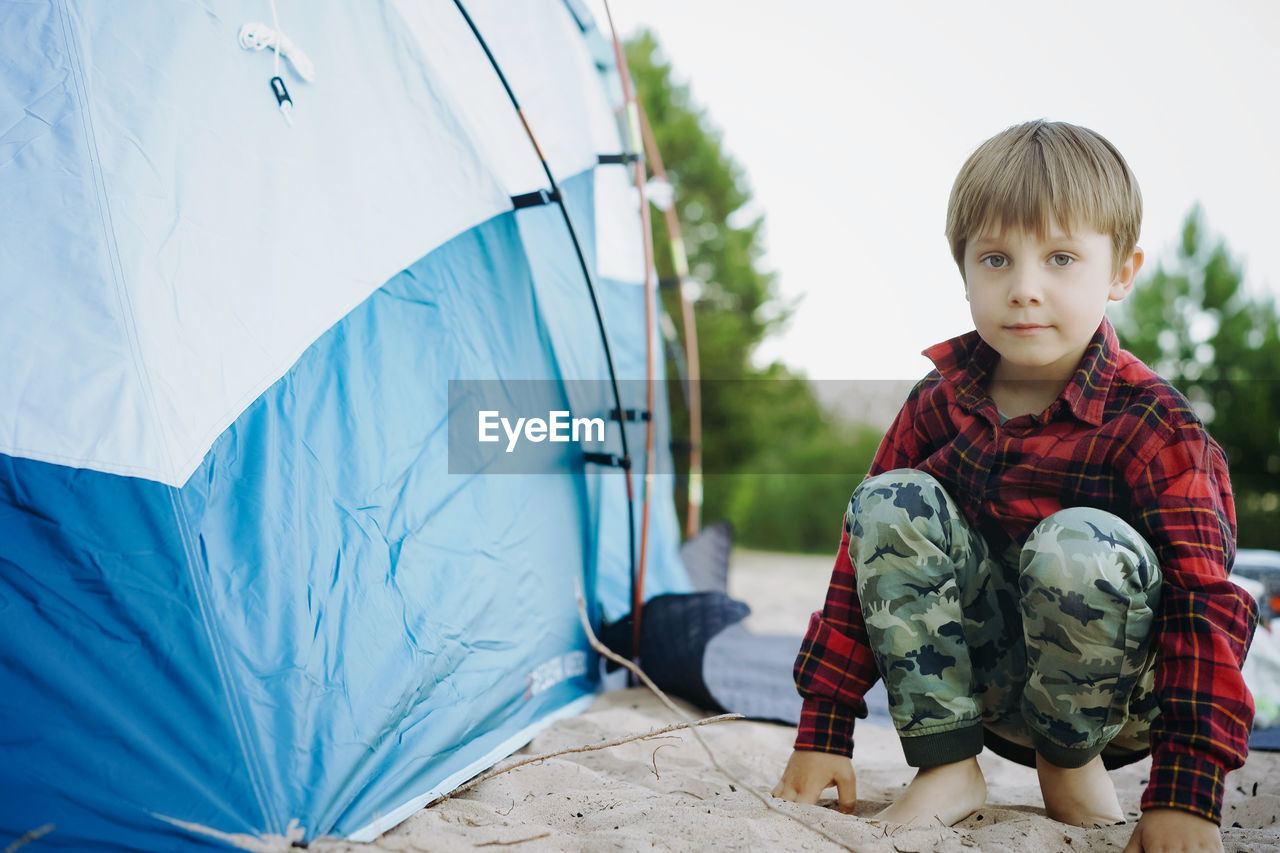 portrait of cute girl sitting on tent