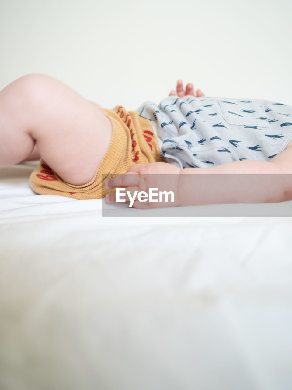 Midsection of baby lying on bed