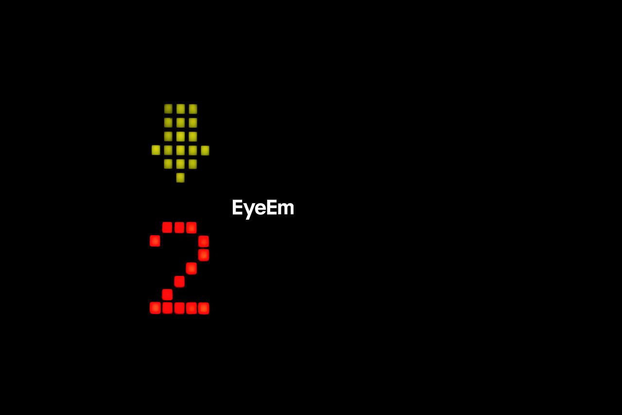 Close-up of illuminated number and arrow symbol against black background