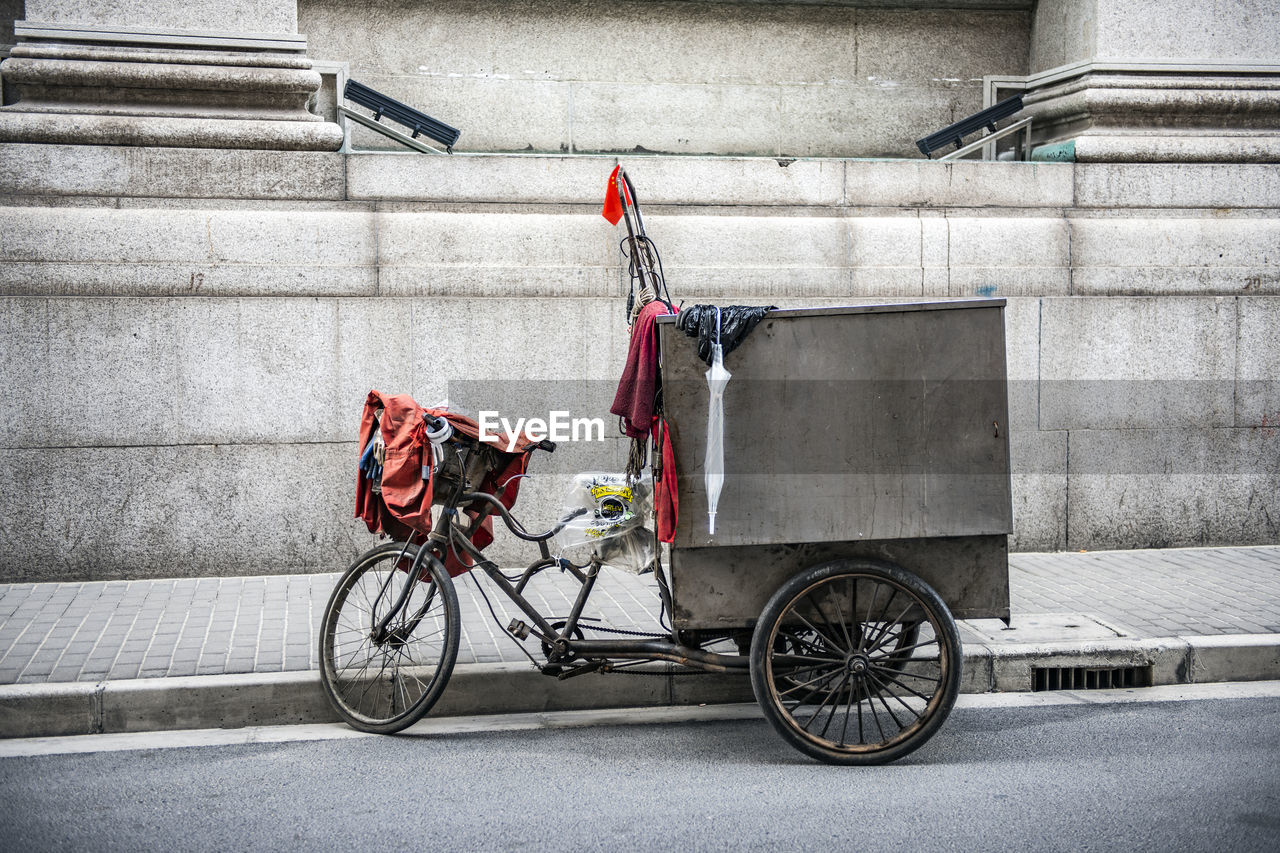 BICYCLE PARKED BY WALL