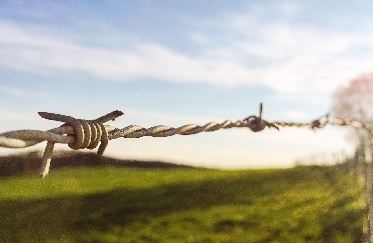 CLOSE-UP OF BARBED WIRE AGAINST SKY