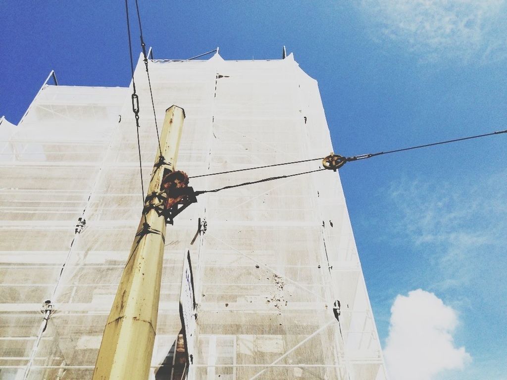 Low angle view of power lines against building