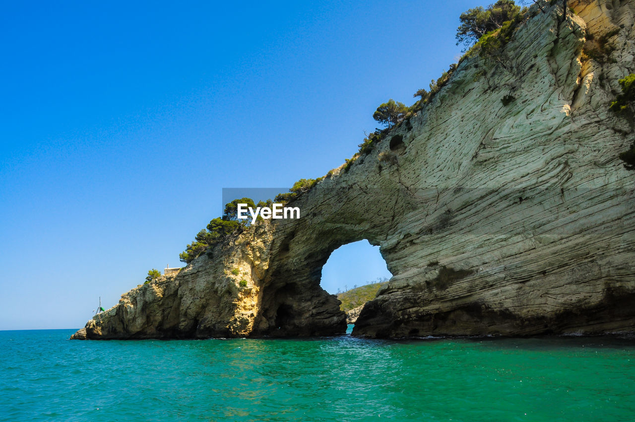 ROCK FORMATION IN SEA AGAINST CLEAR BLUE SKY