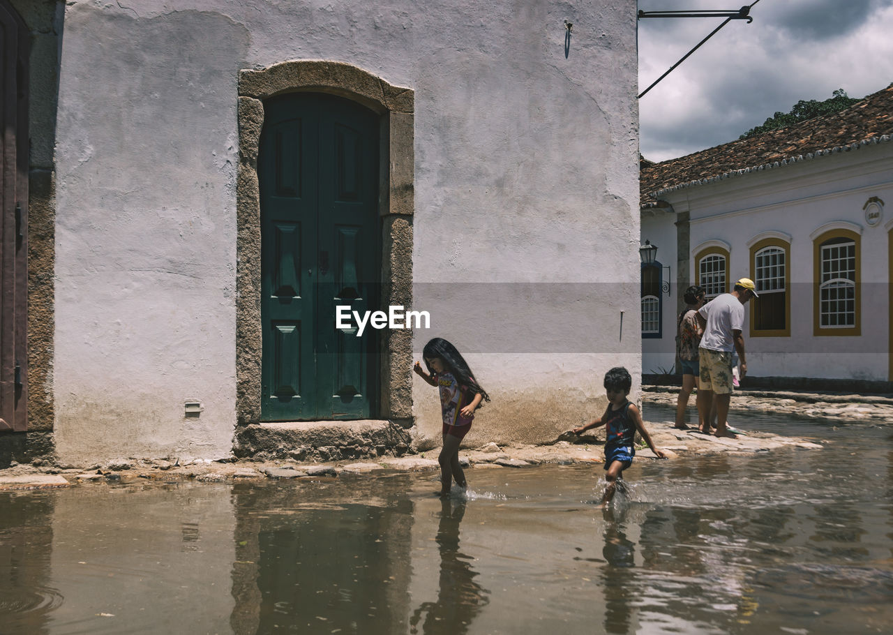 REAR VIEW OF PEOPLE STANDING AT RIVERBANK