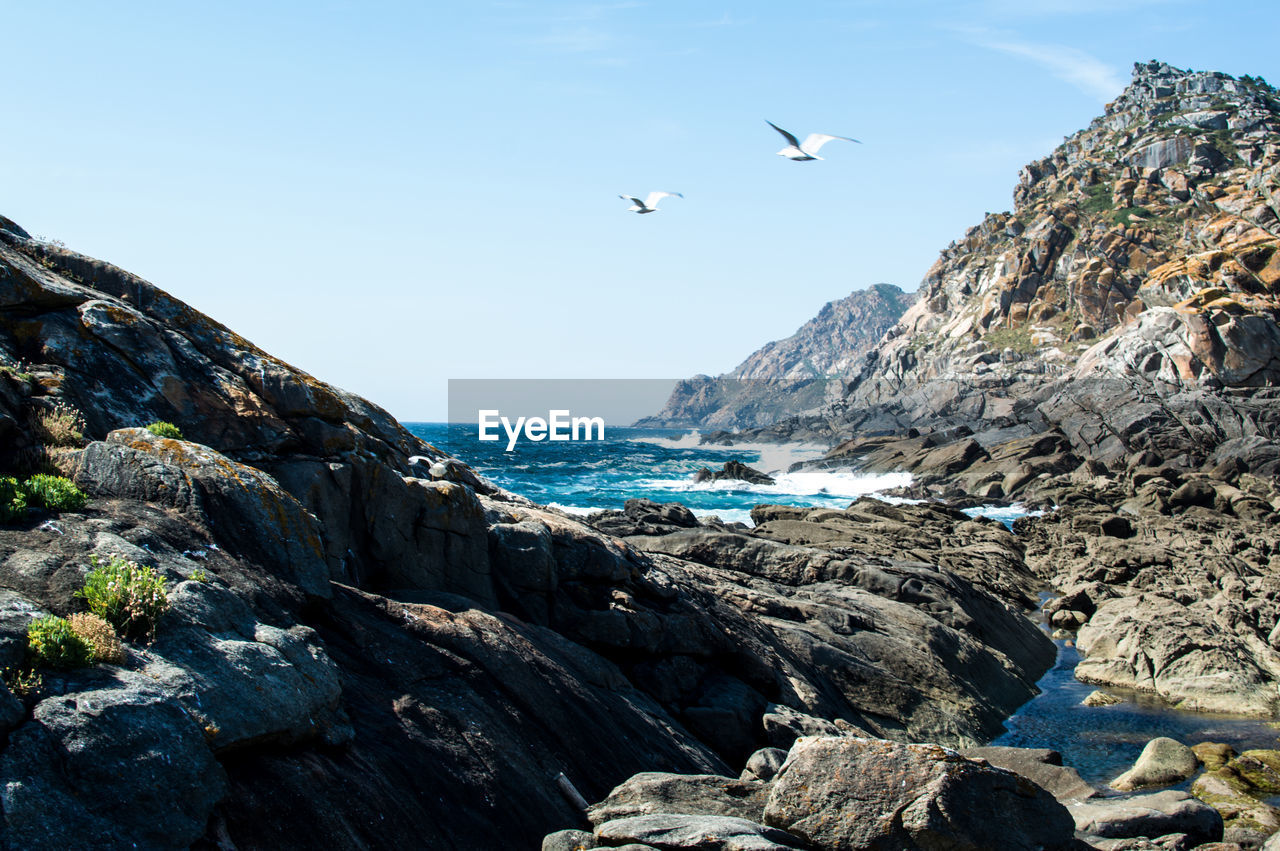 Rock formations by sea against sky