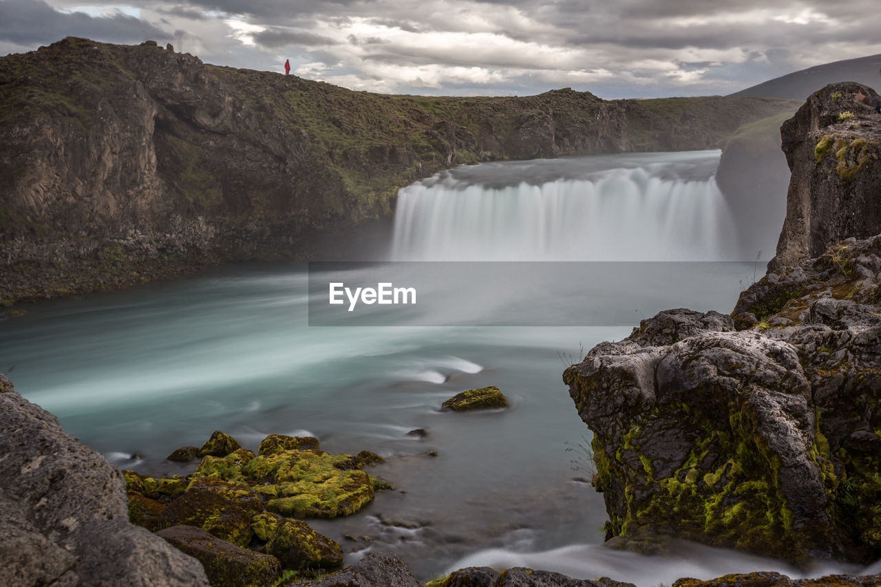 SCENIC VIEW OF WATERFALL AMIDST ROCKS