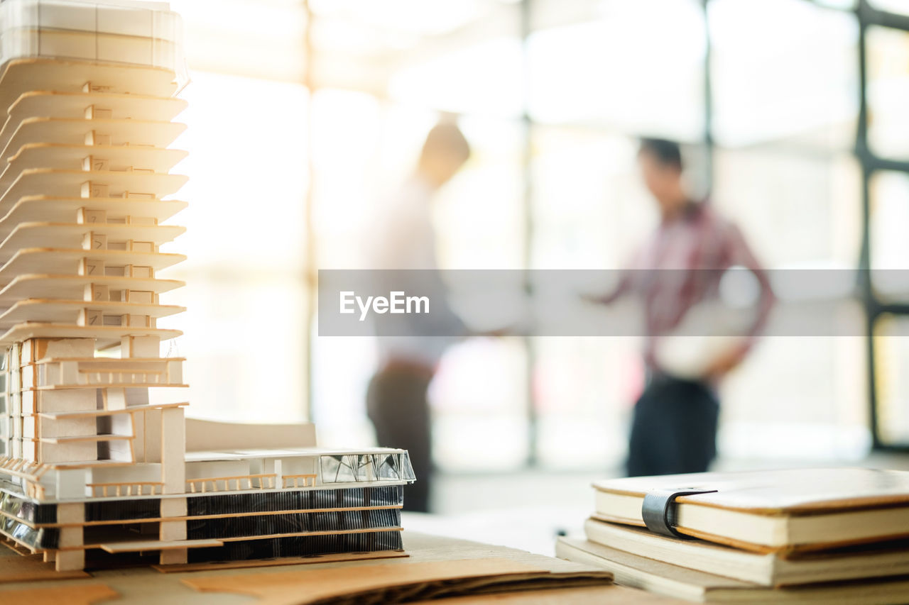 Close-up of building model on desk with business colleagues discussing in background