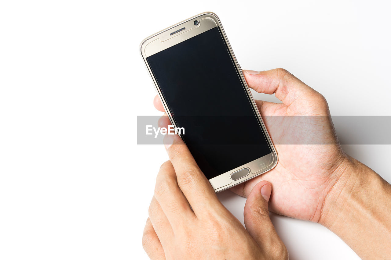 Cropped hands of person holding smart phone against white background