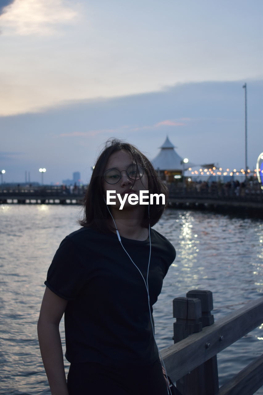 Portrait of young woman standing against sea against sky