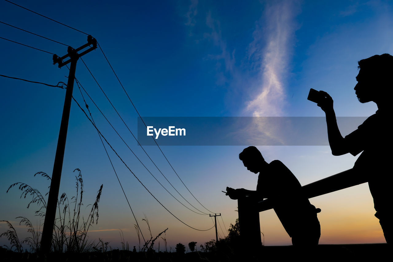 LOW ANGLE VIEW OF SILHOUETTE MAN STANDING AGAINST SKY DURING SUNSET