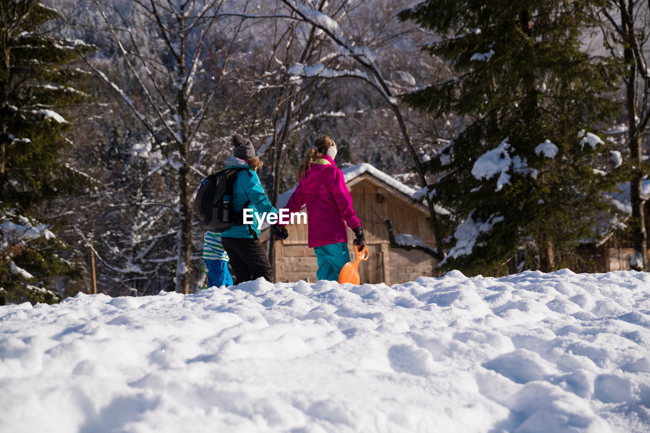 Mother with daughter and son walking on snow covered land in forest