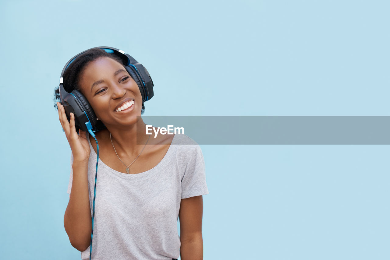 Young woman listening music against colored background