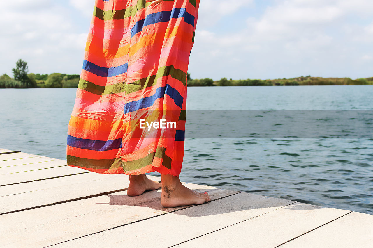 LOW SECTION OF PERSON STANDING ON PIER OVER LAKE