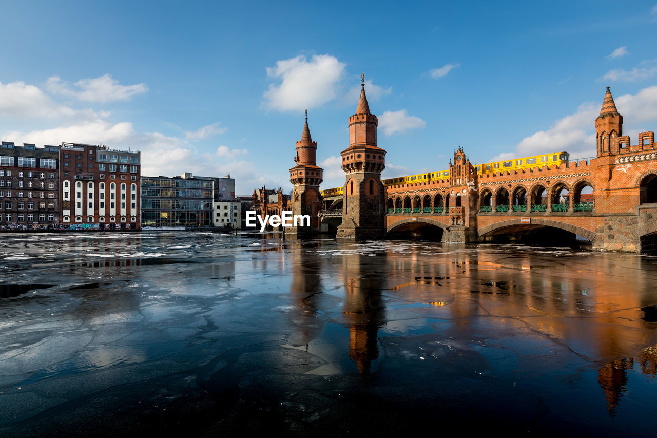 Oberbaum bridge over frozen spree river against sky